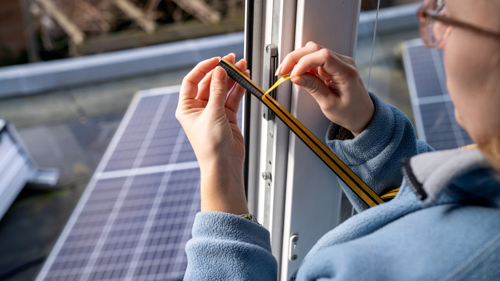 Dec 1 blog close-up of homeowner putting in weather strips on window