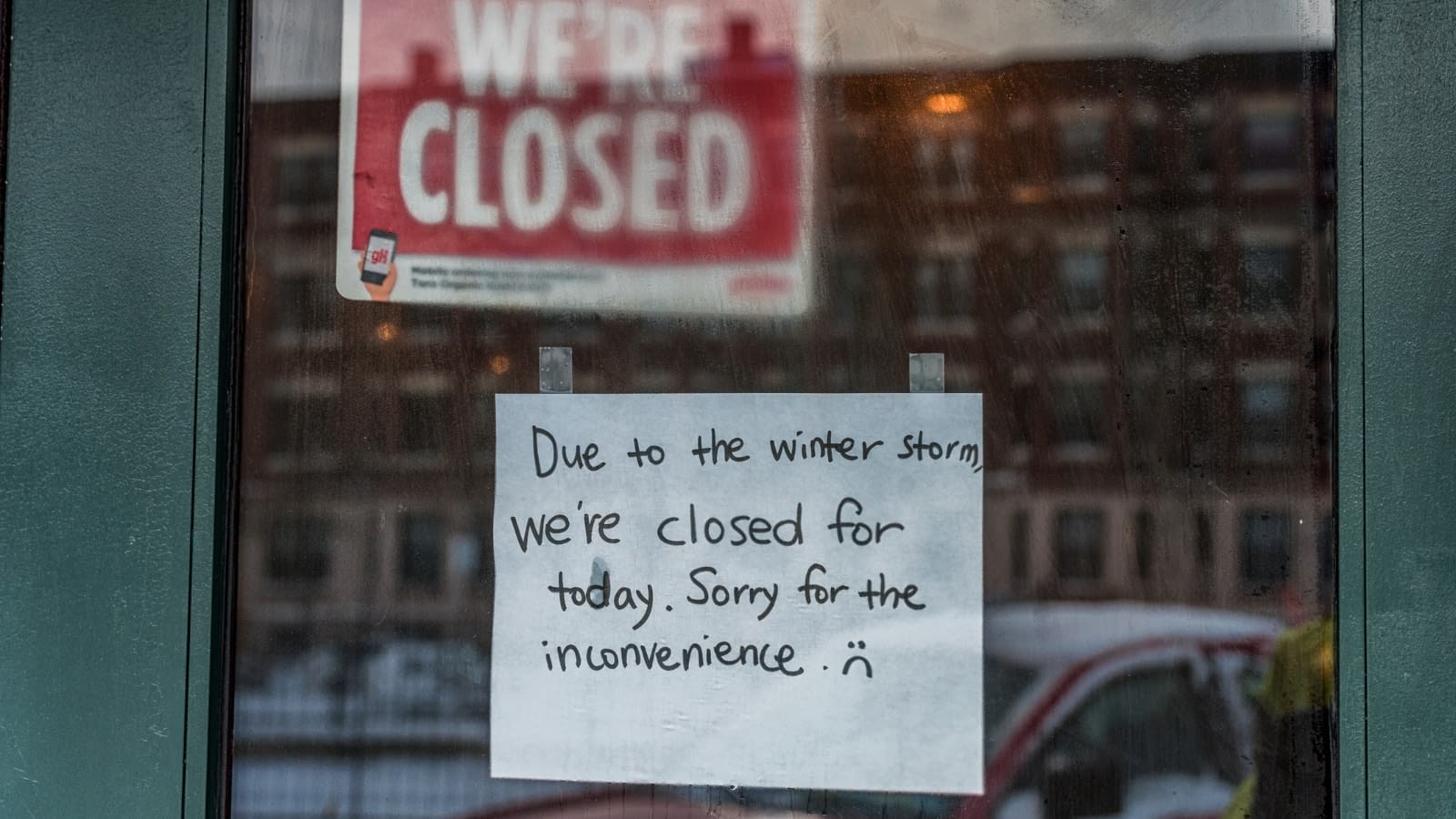 close-up of sign on shop window saying closed due to weather